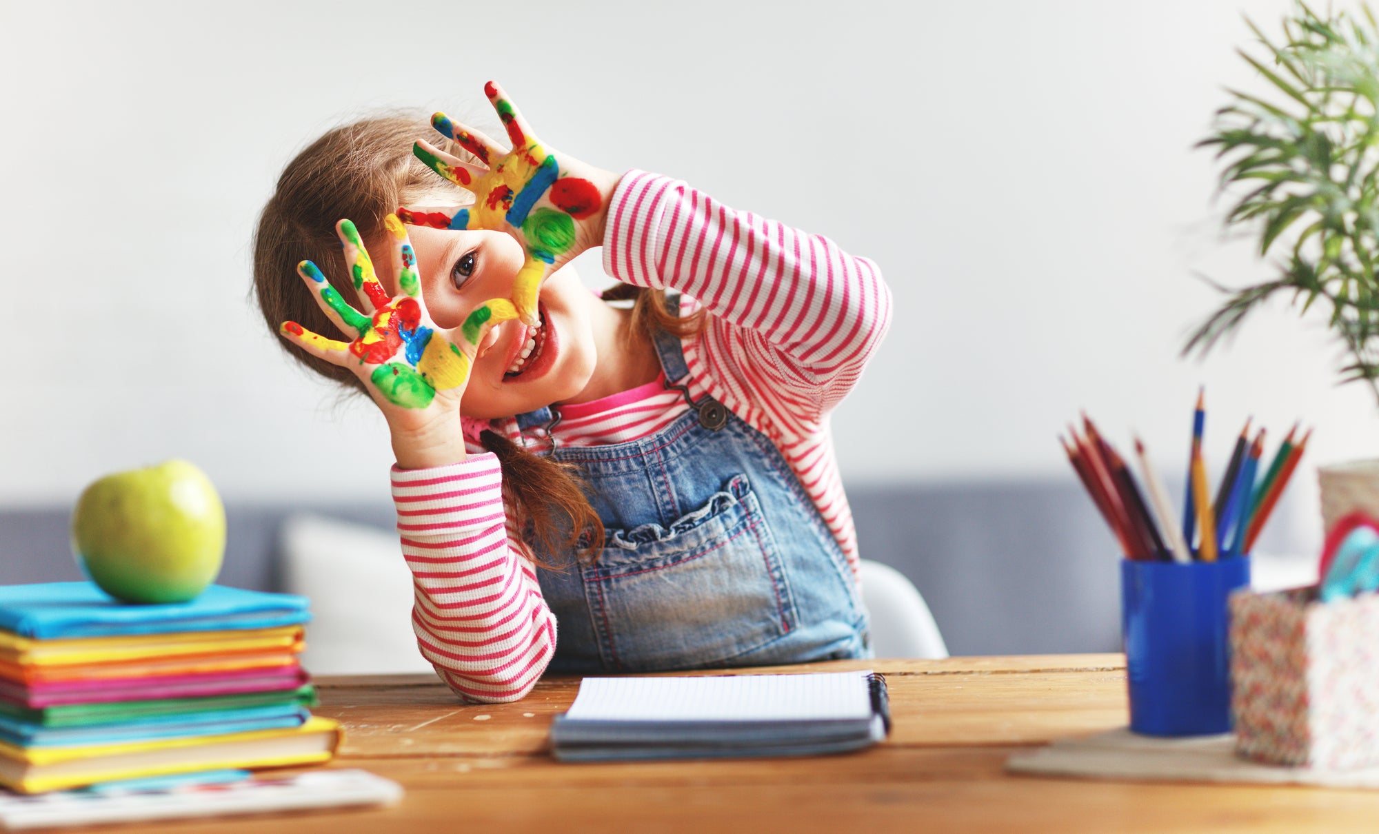 young girls at a desk with colorful paint on her hands