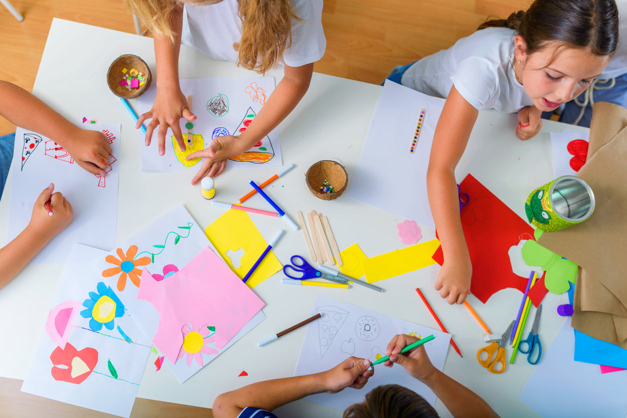 young students with craft supplies on a table creating a project together